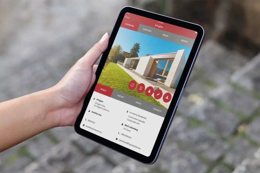 Hand holds tablet displaying fire safety inspection app with modern house, Newport Beach, CA.