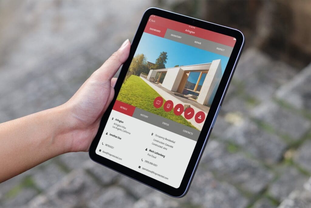 Hand holds tablet displaying fire safety inspection app with modern house, Newport Beach, CA.