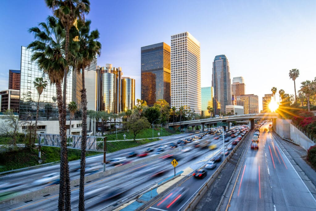 Sunset view of busy Newport Beach, CA highway with modern skyscrapers, ideal for Fire Safety Company.